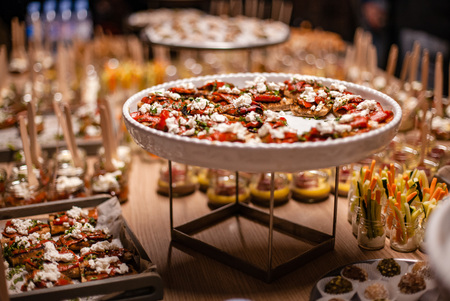 Big table full of appetizing snacks on plate and with sticks.