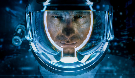Close-up of man wearing helmet with glowing blue color inside looking seriously at camera.