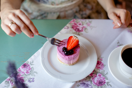 Woman eating a cake in a cafe. Cake with strawberries and currants.の写真素材