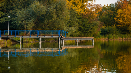 Lakeside with wooden deck extended out into water. Autumn.の写真素材