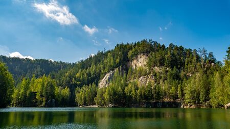 Lake and ancient pines growing between them located in rock city Adrspach, National park of Adrspach, Czech Republicの写真素材