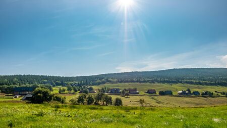 Green field, houses and bright sun.