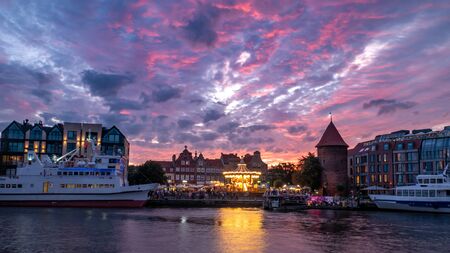 Evening view with spectacular sunset at the old town of Gdansk (Fish Market) with carousel and ship.