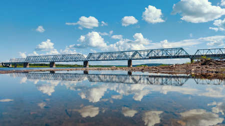 railway bridge over the river against the blue sky with cloudsの写真素材