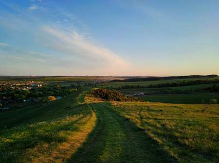 road among green grass on a hilltop near the countryside against a beautiful evening sky