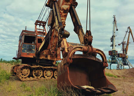 a large mining excavator and huge cranes on a sand quarry against a blue cloudy skyの写真素材