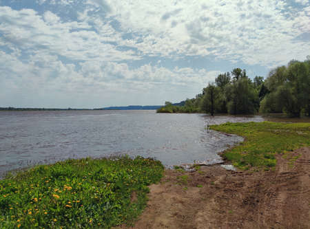 beautiful blue sky with clouds over the river and the green shore after the spill