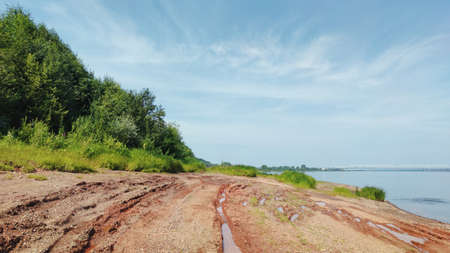 panoramic landscape with a green slope near the river bank against the blue skyの写真素材
