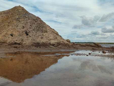 sandy mountain on the river bank against the blue cloudy skyの写真素材