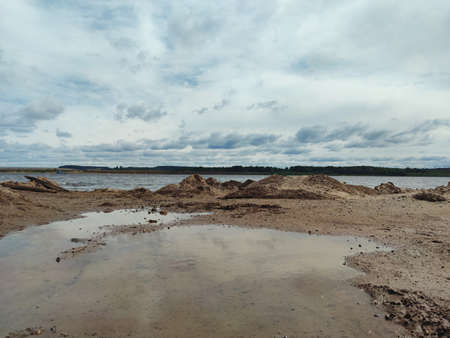 sandy river bank against the backdrop of a cloudy blue skyの写真素材