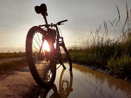 bike on the side of the road in the field against the evening rays of the sun at sunsetの写真素材