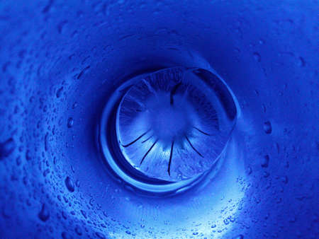 abstract and creative photo with a piece of ice in a tube with blue backlightの写真素材