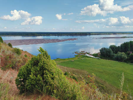 view from the mountain to the river against the blue sky with clouds