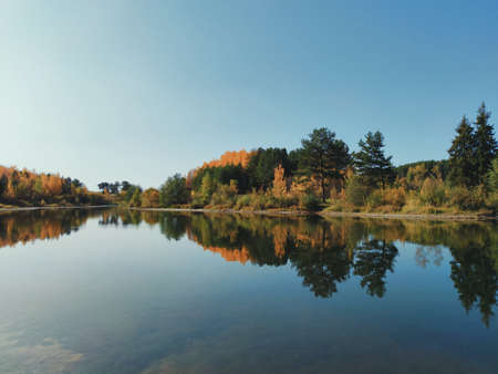 autumn landscape with reflection of trees on the lake surfaceの写真素材