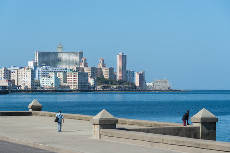 Man in the wall of the Malecon with the modern city in the background, a very popular place in Havana where the population rests among many other activities. Havana. Cuba January 2, 2109のeditorial素材