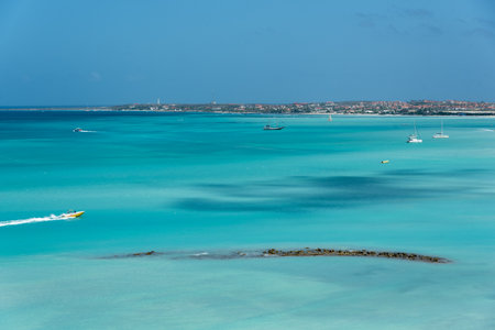 Fast motorboat crossing a beach in aruba surrounded by a reef visible on the surface. Palm Beach. Aruba February 24, 2019のeditorial素材