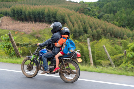 Man and boy on a motorcycle on rural road with crop background. Cauca's Valley . Colombia November 30, 2019.のeditorial素材