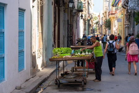 Street vendor of vegetables in the narrow street of Old Havana, with tourists of pedestrians. Havana. Cuba. January 10, 2020.のeditorial素材