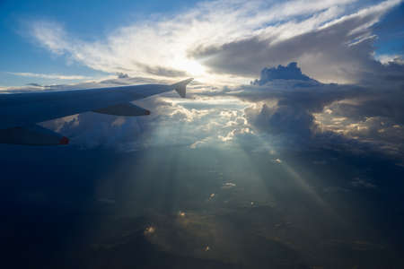 Aerial view of clouds and blue sky with sun rays from airplane windowの写真素材