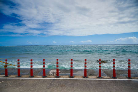 Red and white traffic barrier on the seashore with blue sky.の写真素材
