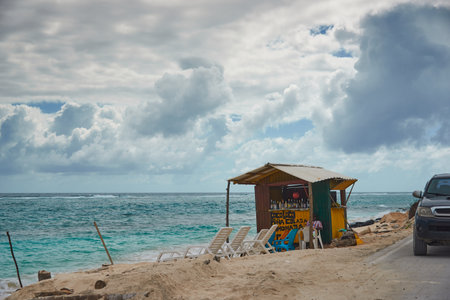 Small wooden warehouse for alcoholic beverages on the shore of a sandy beach with the road on the other side. San AndrÃ©s island. Colombia. December 12, 2020.のeditorial素材