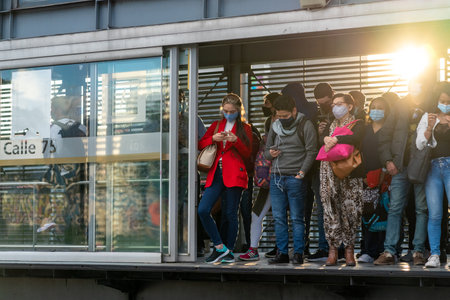 Passengers at the door of a transmilenio station waiting for the bus in the afternoon light...