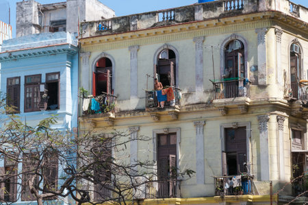 Man on a balcony of an old typical building with colored sheets drying on the railing in a street in Old Havana. Havana. Cuba. May 11, 2015.のeditorial素材