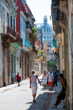 Passersby and neighbors in a neighborhood of old Havana with colonial-style facades with the city's capitol building in the background. Havana. Cuba. May 11, 2015のeditorial素材