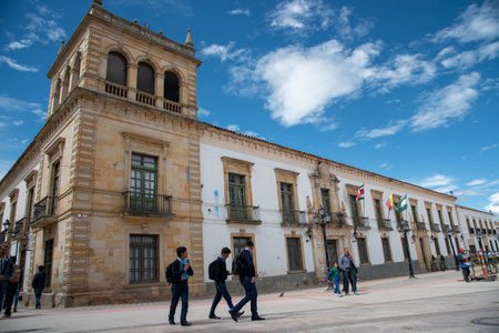 Passers-by in front of a colonial-style building in the city of Tuja on a sunny day. Boyaca....