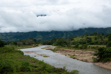 River in a landscape with mountains in the background covered in mist. Colombia.の写真素材