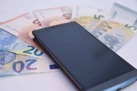 a smartphone and euro banknotes, as symbol for phone billの写真素材