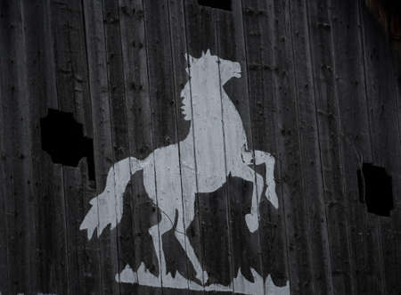 white horse symbol painted on an old wooden wall of a barnの写真素材