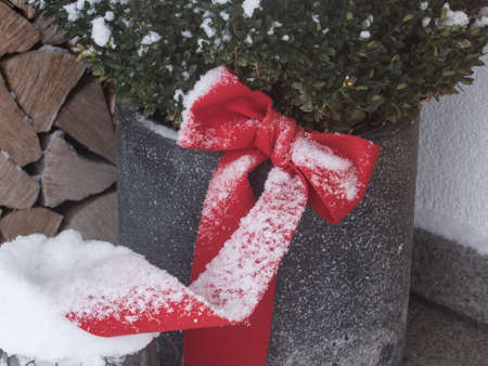 a christmas present wrapped with a red loop and covered with snowの写真素材