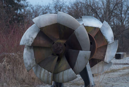 a rusty and old francis turbine, standing outdoors, on a sunny dayの写真素材