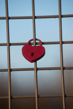 red heart shaped lock on a fence, symbol of loveの写真素材