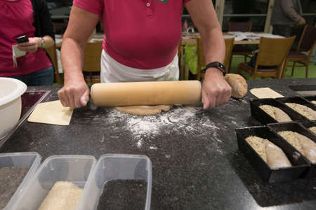 woman using a rolling pin forming bread dough in a kitchen