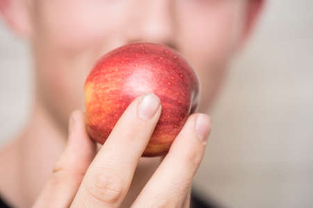consumer holding an apple in their hand, in front of the mouthの写真素材
