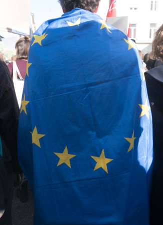 EU citizen wearing a blue EU flag with yellow stars as a capeのeditorial素材