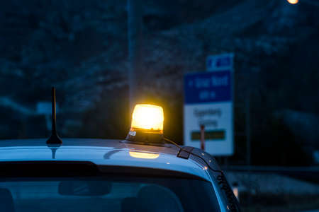 orange flashing light on a car roof, turned on, at twilight