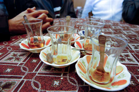 sitting in a teahouse, small glass with tea a spoon and saucers