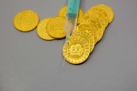 golden bitcoin coins and a syringe,  representing the electronic currencyの写真素材