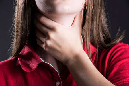 a person with a sore throat touching the painful areaの写真素材