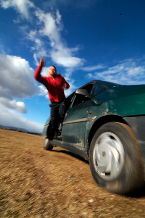 a stuntman performing a stunt, falling out of a moving carの写真素材