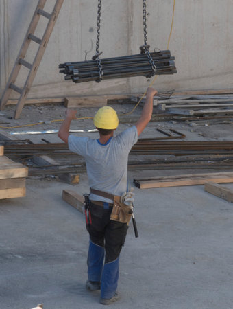 Worker with construction crane with heavy load on construction sideの写真素材