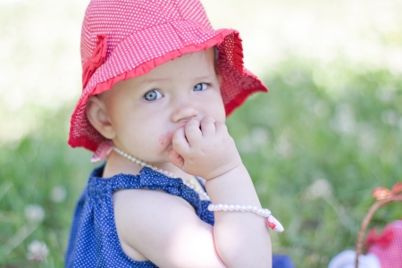 cute baby girl is eating strawberries in summerの写真素材