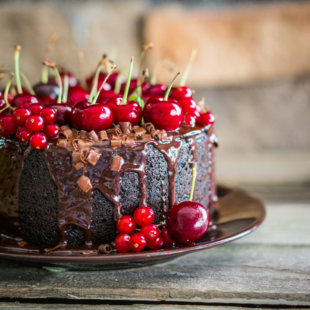 Chocolate cake with cherries on wooden background