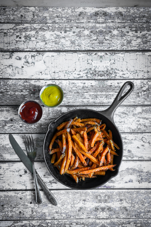 Sweet potato fries in cast iron skillet on wooden backgroundの写真素材