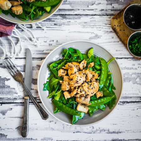 Grilled chicken with spinach,arugula and peas on rustic wooden backgroundの写真素材