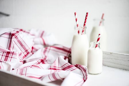Milk jar with red striped straws on white wooden backgroundの写真素材