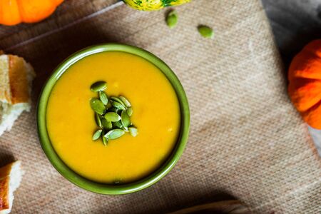 Creamy pumpkin soup with seeds on wooden backgroundの写真素材